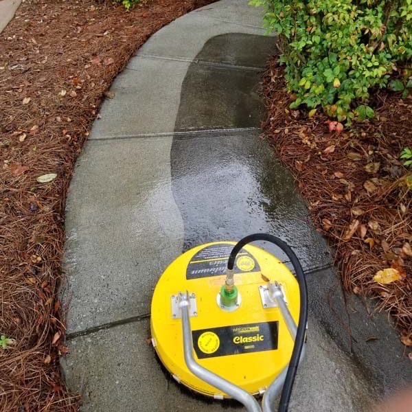 Surface cleaner on a concrete walkway leaving a clean path